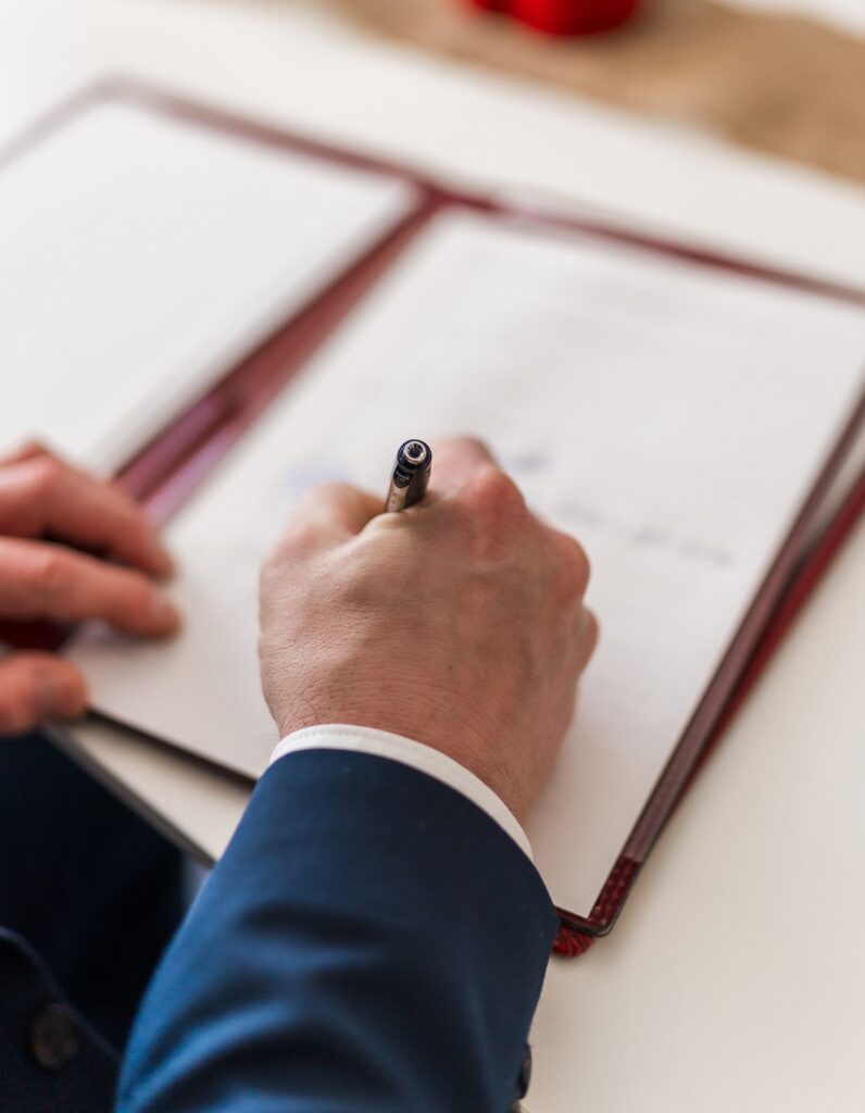 Close-up of a businessman signing a document in a formal office environment.